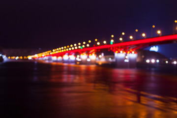 Fototapeta na wymiar background of the defocused lights of the night city, a bridge across the river