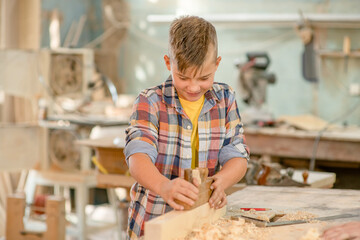 Young boy planed wood in a workshop