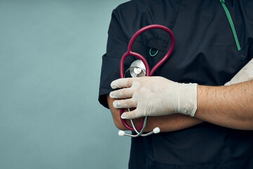 Young male doctor in protective gloves and with a stethoscope. Professional clothing.