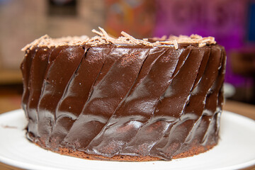 A home baked delicious chocolate cake with chocolate sprinkles on a wooden kitchen work top