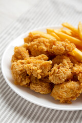 Homemade Fried Chicken Bites and French Fries on a plate, side view. Close-up.