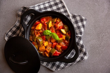 Cooked various chopped vegetables with herbs in a black cooking pot