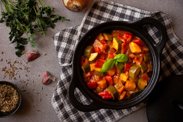 Cooked various chopped vegetables with herbs in a black cooking pot