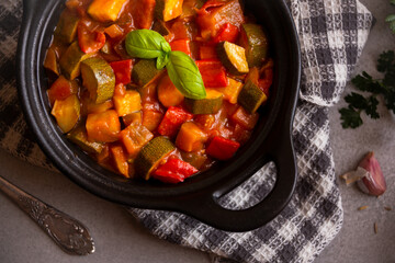 Cooked various chopped vegetables with herbs in a black cooking pot