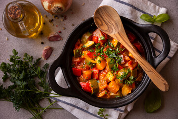 Cooked various chopped vegetables with herbs in a black cooking pot