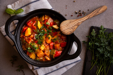 Cooked various chopped vegetables with herbs in a black cooking pot