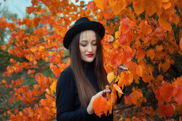 girl with red lipstick in a hat and mask on the background of an autumn tree