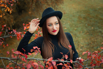 Fototapeta na wymiar girl with red lipstick in a hat and mask on the background of an autumn tree