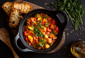 Cooked various chopped vegetables with herbs in a black cooking pot