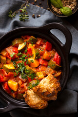 Cooked various chopped vegetables with herbs in a black cooking pot