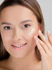 Face care and makeup, a young woman applies Foundation to the skin.