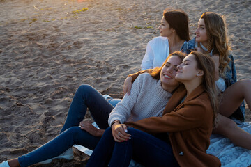 Group of young women on a picnic on the beach, enjoying the sunset. Meeting friends,