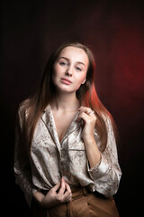 Woman with long, blond hair posing for the camera. Studio, dark background.