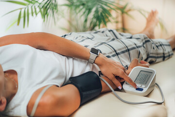 Orthostatic Blood Pressure. Woman Lying on Back and Measuring Blood Pressure on her Arm