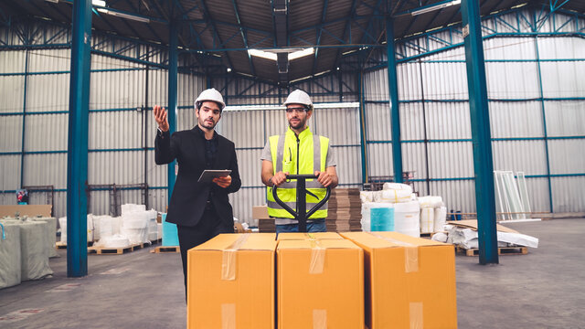 Factory workers deliver boxes package on a pushing trolley in the warehouse . Industry supply chain management concept .