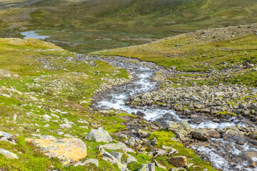 Naklejka na ściany i meble Stream flowing down to the lake in high country landscape