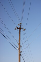 Fototapeta premium old wooden pillar with many wires blue sky background.