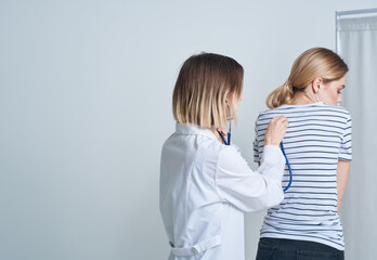 doctor woman in medical gown with stethoscope listens to patient's heart