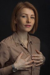 Red-haired young woman with freckles. He's holding his hands on his chest. Disease, breast size...