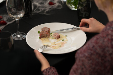 Closeup of woman eating delicious roasted pork meat wrapped in bacon with potato mash. Irish traditional dish wrapped pork loin with roasted garlic