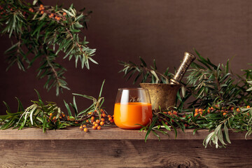 A glass of sea buckthorn juice with fresh berries on an old wooden table.
