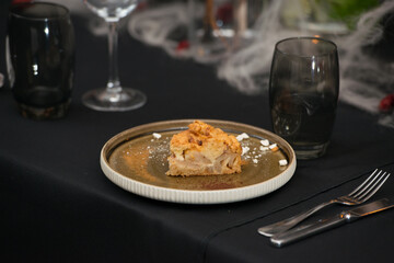 Delicious apple pie charlotte with caramel on the plate on black tablecloth