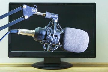 Condenser, studio microphone on the background of a computer monitor