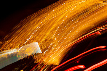 Bright orange neon glowing fast moving streams of light, along a trajectory. Fast energy flying wave line with flash lights. Swirl trace path on black background.
