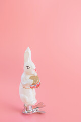 Old vintage Christmas toy - bunny with a drum. Festive new year concept, pastel pink background. Minimalism. XX century, antiques..