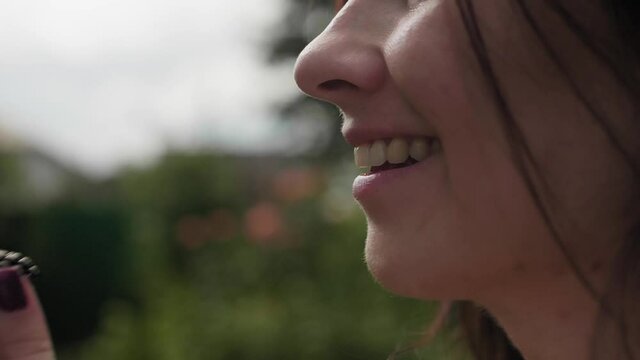 Side view of girl eating dewberry in bacl yard of house