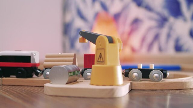 Toy wooden railway. Small electrical train moving on rails with wagons.