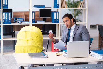 Young male employee looking after newborn at workplace