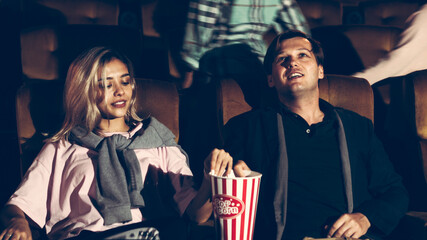 Audience walking to seats in the movie theater, watching film and eating popcorn.