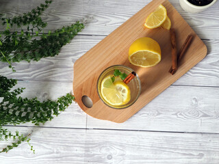 Glass of lemonade with lemons, drink with cinnamon stick on a wooden board - 392424281