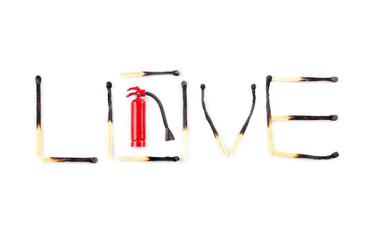 Word love made of burnt matches and a miniature red fire extinguisher. Burned by love creative concept.