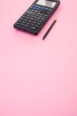 Vertical shot of a calculator and a pen on a pink background