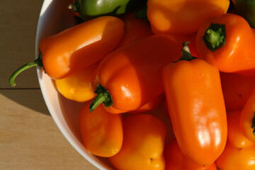 Orange mini bell peppers of the 'Lunchbox' variety (sweet snacking pepper) in a round white bowl, closeup, top view