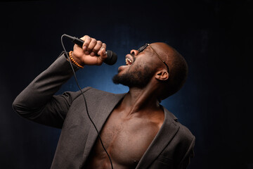 A black African American is emotionally singing into a microphone. Close-up studio portrait.