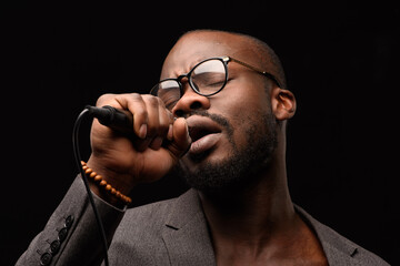 A black African American is emotionally singing into a microphone. Close-up studio portrait.