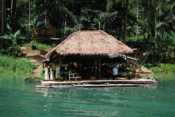 Fototapeta na wymiar colourful traditional village hut with thatched roof on the river bank in the middle of the jungle