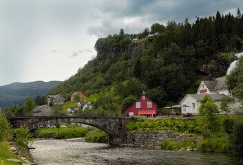 Fototapeta na wymiar Typical Norwegian house near one of the most popular waterfalls in Norway - Steinsdalsfossen, on the Fosselva river in western Norway