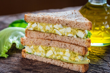 Sandwich with avocado and egg on wooden background