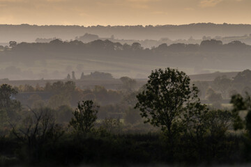 Hills and trees in mist at a stormy sunset