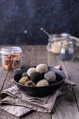 Raw energy bites balls prepared with natural ingredients on wooden background