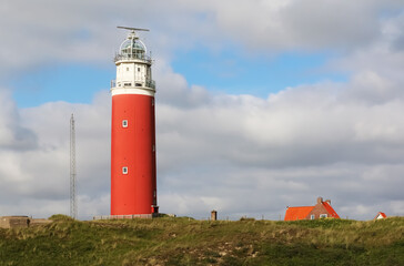 
West Frisian Islands in the Netherlands. Red lighthouse on the sandy shore of Texel Island.