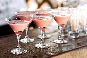 several martini glasses with pink cocktail are on the bar table.