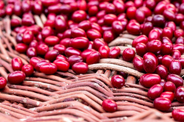 Fresh dogwood red berries on wooden basket. Fresh cornel berries. Selective focus.