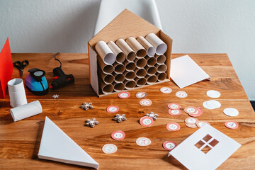 Process of making handmade advent calendar house from toilet paper rolls and carton box....
