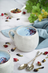 A cup of hot blue moon butterfly milk tea latte with ingredients top with crushed blue pea and rose petals, its caffeine free beverage before bed and an age-old remedy for sleeplessness. 