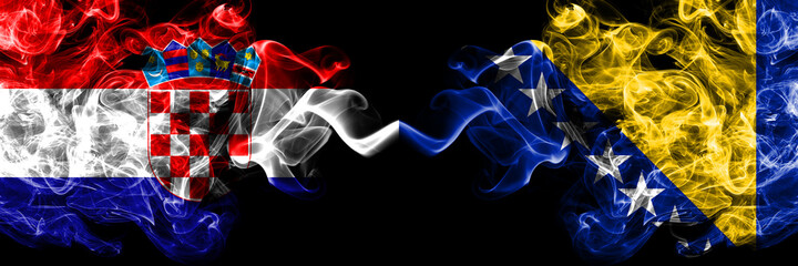 Croatia, Croatian vs Bosnia and Herzegovina, Bosnian, Herzegovinian smoky mystic flags placed side by side. Thick colored silky abstract smoke flags.